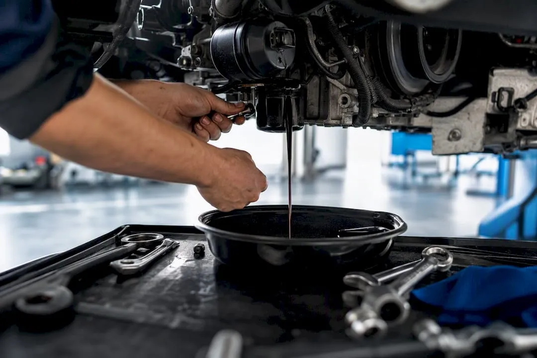 Mechanic draining oil in workshop