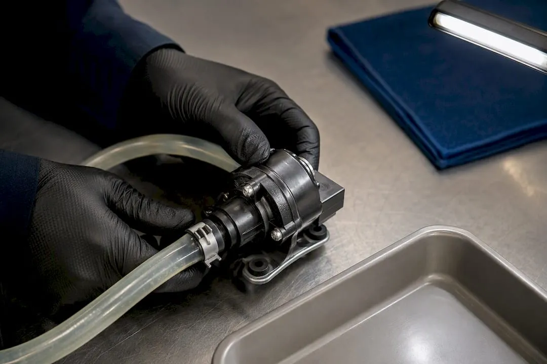 Technician inspecting inverter coolant pump and hose